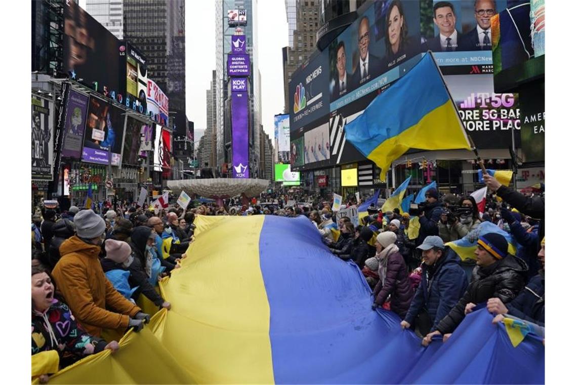 Immer mehr Russen rufen zur Beendigung des Krieges auf Demonstranten stehen um eine große ukrainische Flagge versammelt auf dem Times Square, um gegen die russischen Angriffe auf die Ukraine zu protestieren. Foto: Seth Wenig/AP/dpa