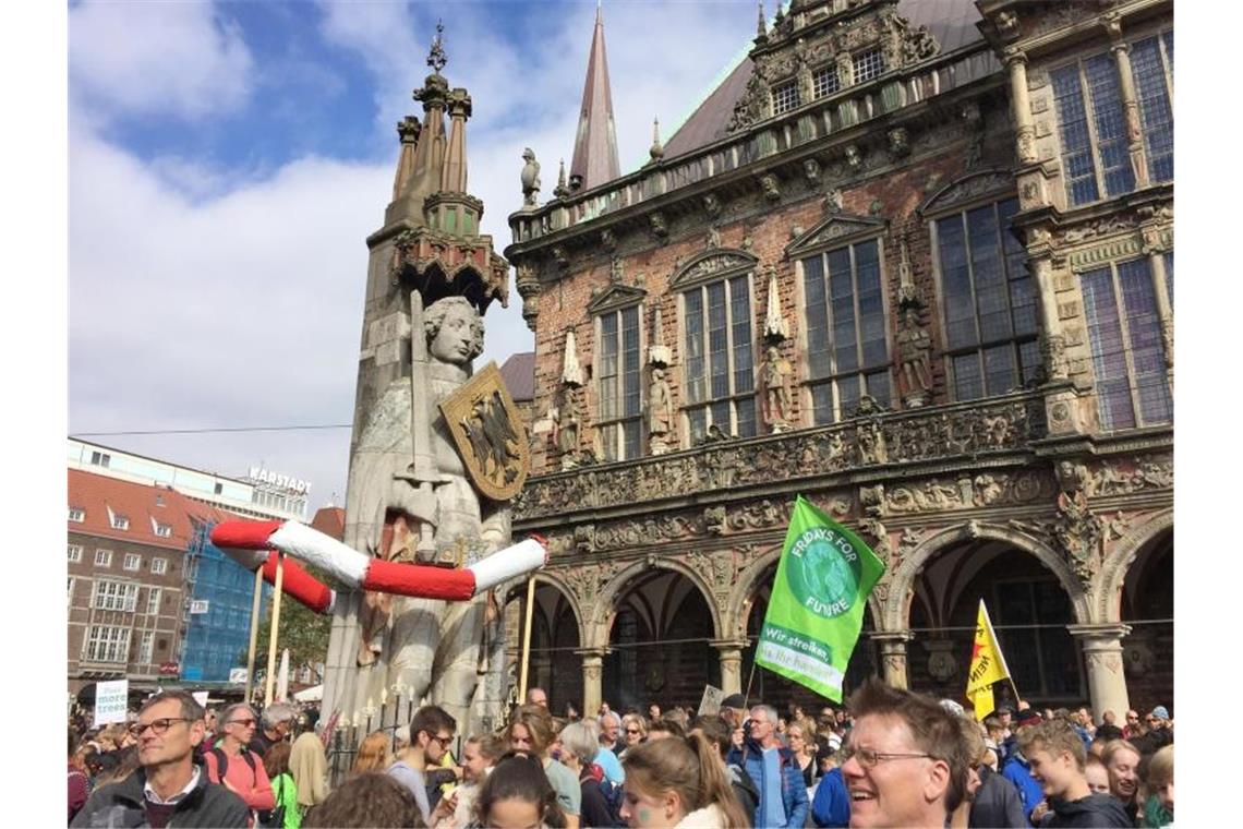 Demonstranten stehen vor dem historischen Rathaus und dem Roland in Bremen. Foto: Friedemann Kohler