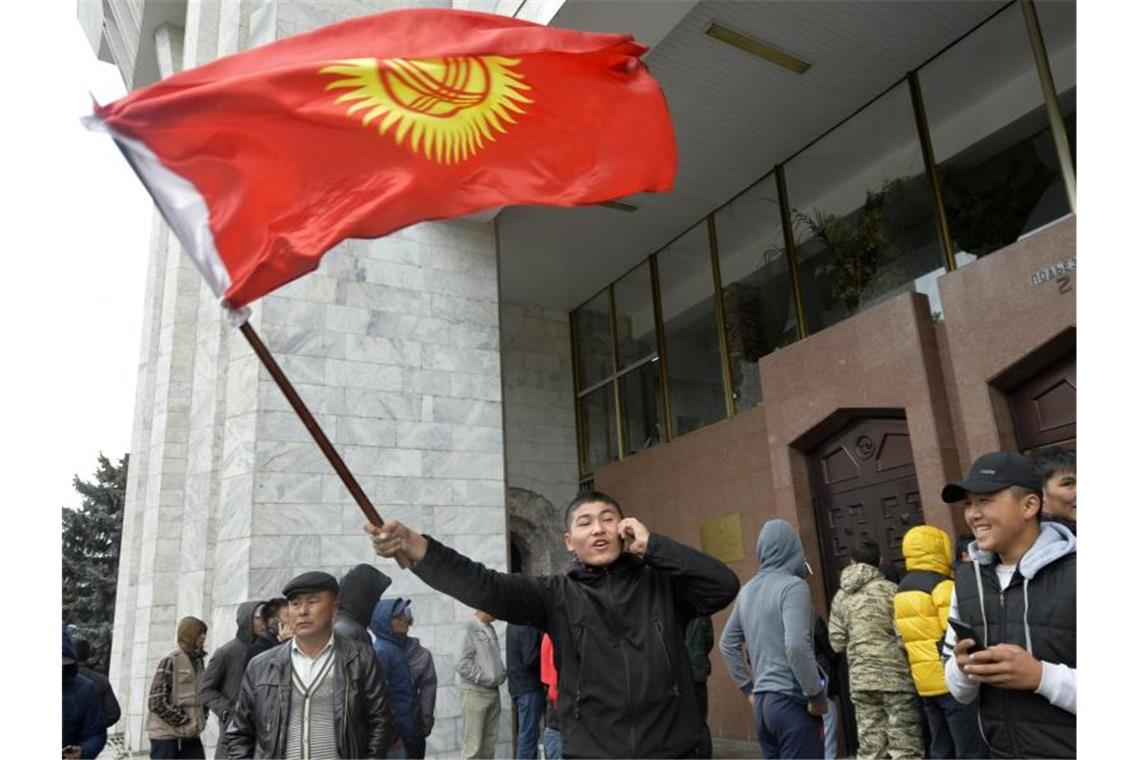 Tausende Menschen bei neuen Protesten in Kirgistan Demonstranten stehen vor dem Regierungsgebäude in Bischtek. Unter dem Druck massiver Proteste hatte die Wahlleitung im zentralasiatischen Kirgistan die Parlamentswahl für ungültig erklärt. Foto: Vladimir Voronin/AP/dpa