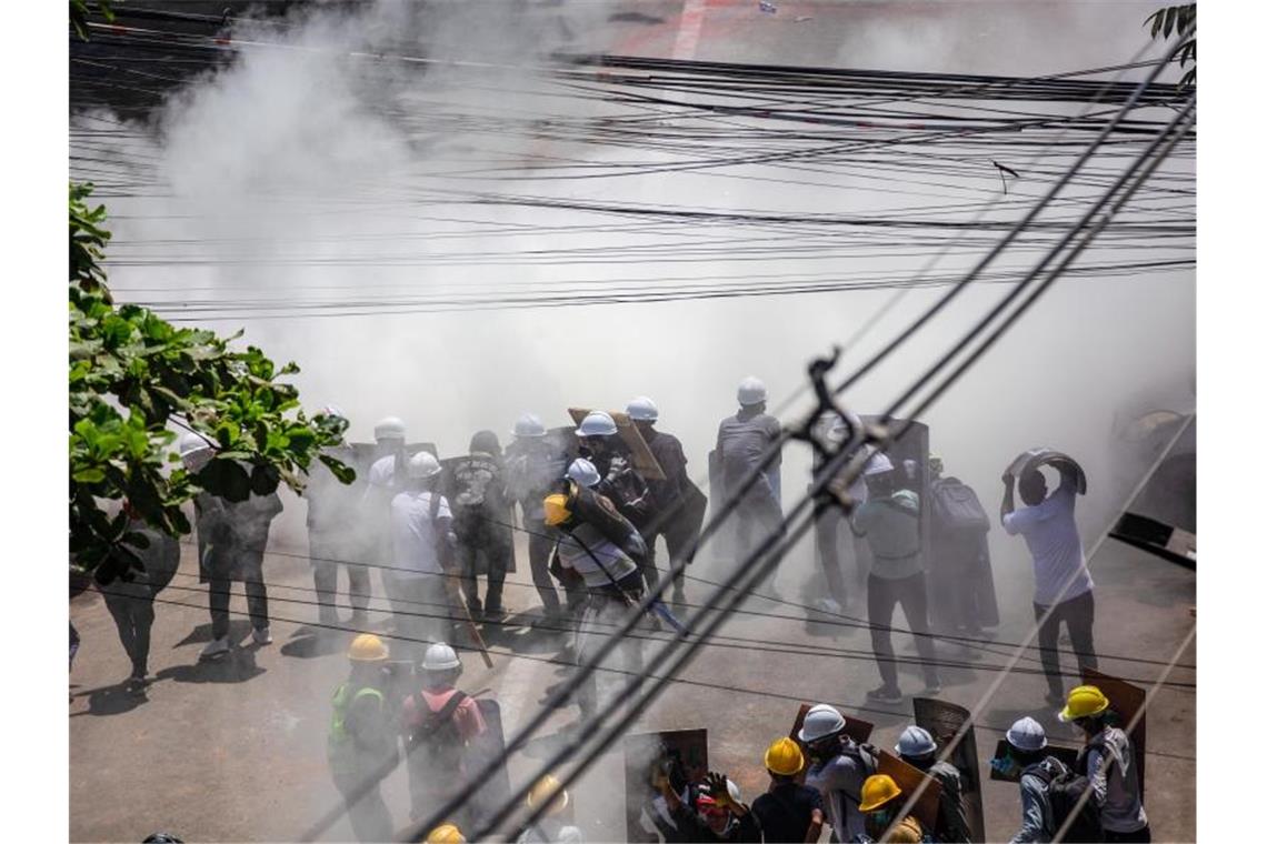 Myanmar trauert um seine Toten - Proteste gehen weiter Demonstranten tragen in Rangun in einer Wolke von Tränengas Schutzhelme, um sich gegen die Gewalt zu schützen. Foto: Aung Kyaw Htet/SOPA Images via ZUMA Wire/dpa