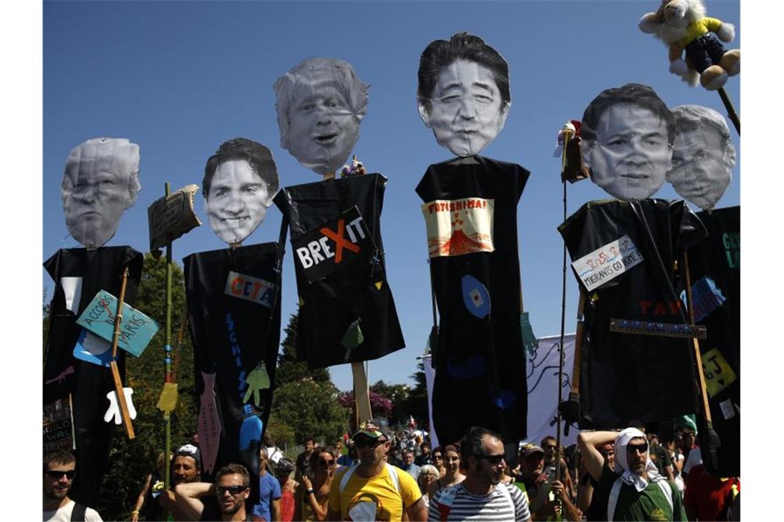 Demonstranten tragen während eines Protestmarschs gegen den G7-Gipfel Figuren, die die teilnehmenden Staats- und Regierungschefs darstellen sollen. Foto: Emilio Morenatti/AP