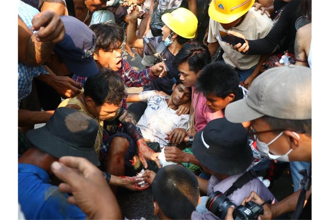 Demonstranten umringen einen Verletzten bei einem Protest gegen den Militärputsch in Yangon. Foto: Uncredited/AP/dpa