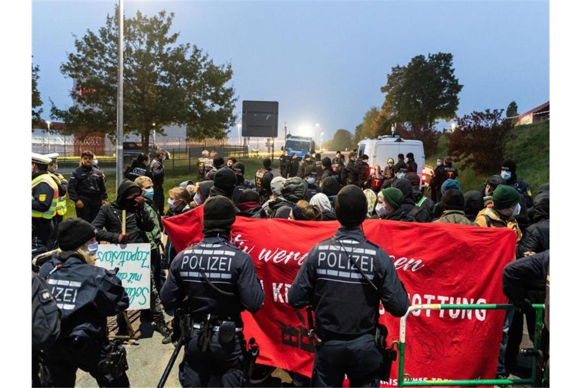 Demonstranten und Demonstrantinnen blockieren den Haupteingang des Waffenherstellers Heckler & Koch. Foto: Silas Stein/dpa