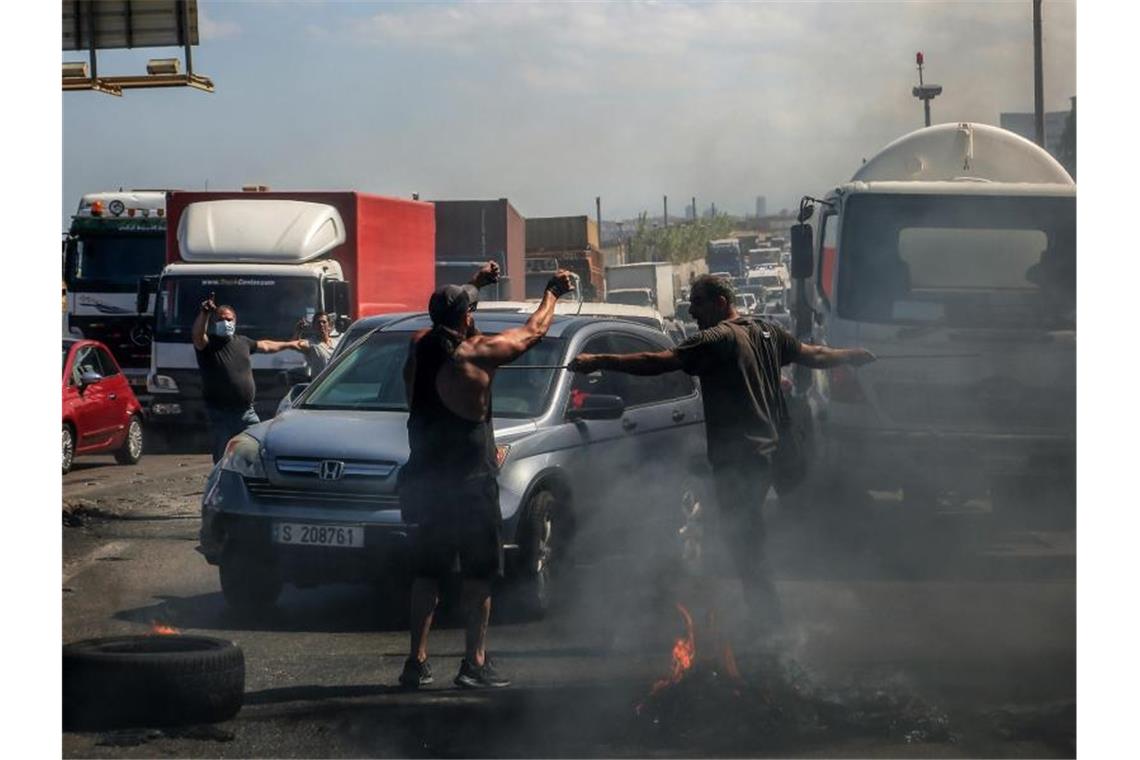 Demonstranten verhindern die Durchfahrt von Autos, während sie eine Hauptstraße, die Beirut mit dem Südlibanon verbindet, mit brennenden Reifen blockieren. Foto: Marwan Naamani/dpa