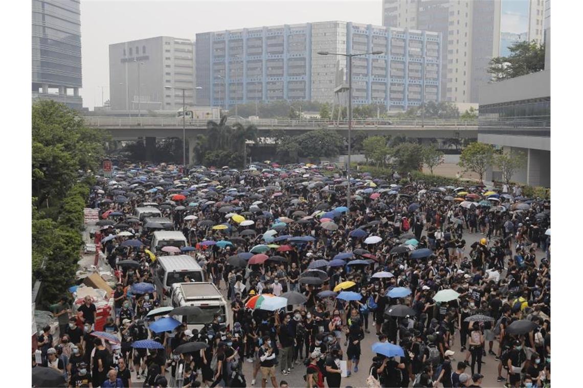 Neue Zusammenstöße in Hongkong - Wasserwerfer auf der Straße Demonstranten versammeln sich auf einer Straße. In Hongkong kommt es seit mehr als zwei Monaten immer wieder zu massiven regierungskritischen Protesten. Foto: Kin Cheung/AP