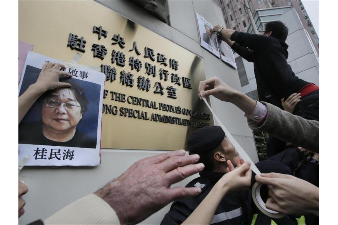 Demonstranten versuchen bei einer Kundgebung ein Foto des Hongkonger Buchhändlers Gui Minhai aus Protest gegen seine Verhaftung am Regierungssitz zu befestigen. Foto: Vincent Yu/AP/dpa