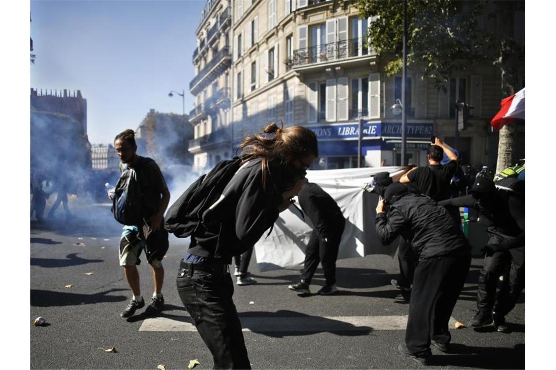 Demonstranten versuchen, sich vor dem Tränengas der Polizei zu schützen. Foto: Thibault Camus/AP
