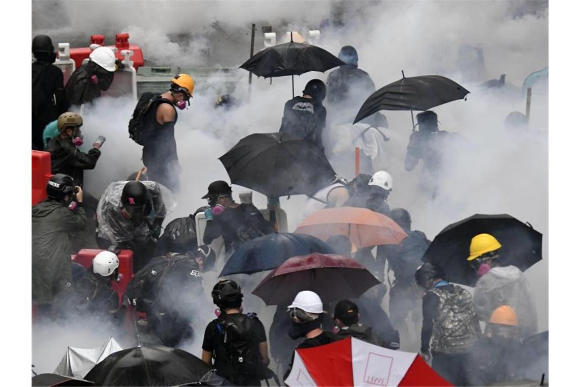 Neue Zusammenstöße in Hongkong - Wasserwerfer auf der Straße Demonstranten versuchen sich vor Tränengas zu schützen. Foto: kyodo