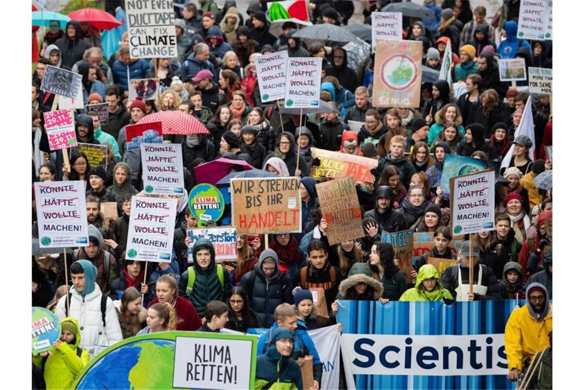 Demonstration gegen Fluchtursachen und Umweltzerstörung Demonstranten von Fridays for Future laufen auf einer Straße und halten Plakate in die Luft. Foto: Tom Weller/dpa/Archivbild