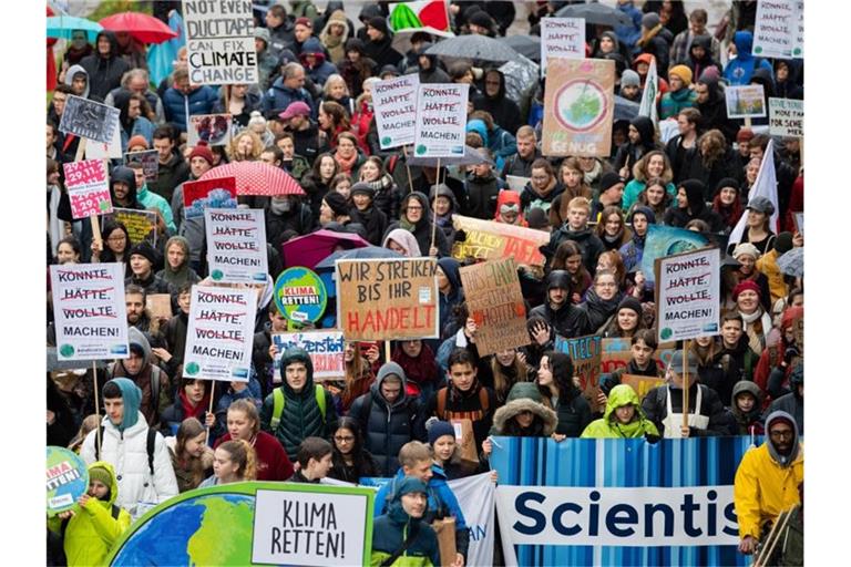 Demonstranten von Fridays for Future laufen auf einer Straße und halten Plakate in die Luft. Foto: Tom Weller/dpa/Archivbild