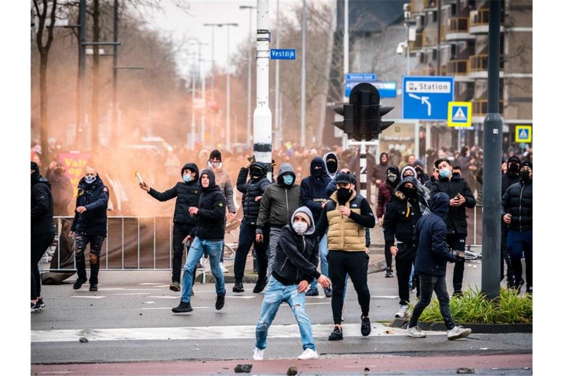 Demonstranten werfen auf einer Straße in Eindhoven mit Steinen. Mehrere hundert Menschen haben vor dem Bahnhof der Stadt gegen die aktuelle Corona-Politik demonstriert. Foto: Rob Engelaar/ANP/dpa