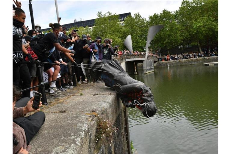 Demonstranten werfen die Statue des Sklavenhändlers Edward Colston in den Hafen von Bristol. Foto: Ben Birchall/PA Wire/dpa