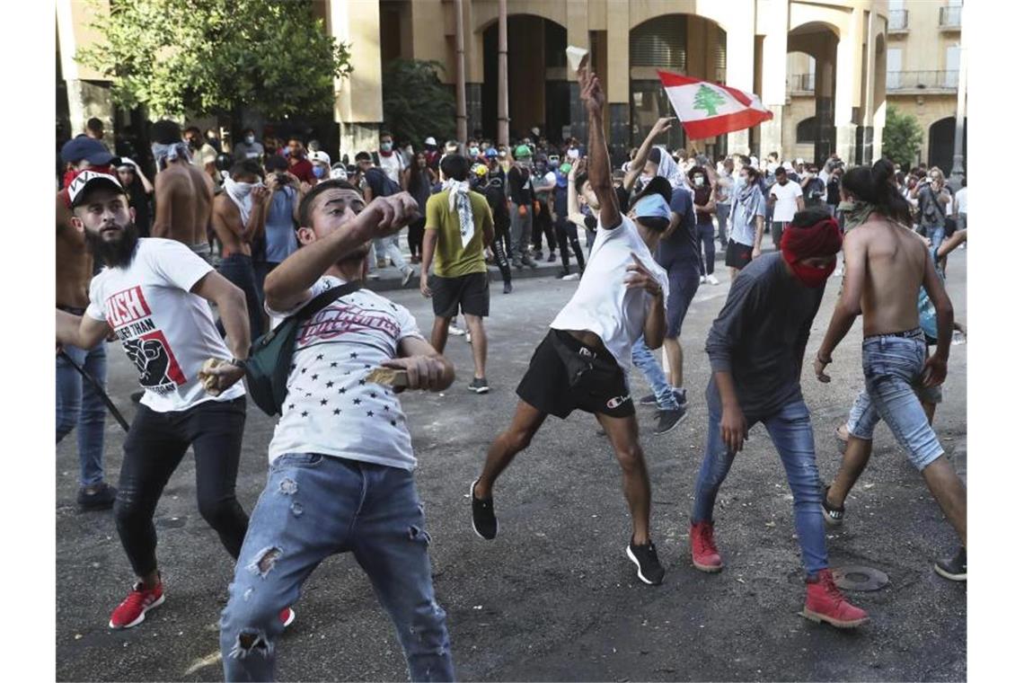 Libanons Regierung tritt nach Explosion zurück Demonstranten werfen in Beirut Steine auf libanesische Bereitschaftspolizisten. Foto: Bilal Hussein/AP/dpa