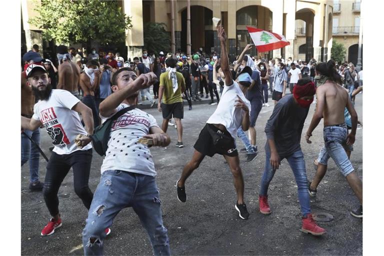 Demonstranten werfen in Beirut Steine auf libanesische Bereitschaftspolizisten. Foto: Bilal Hussein/AP/dpa