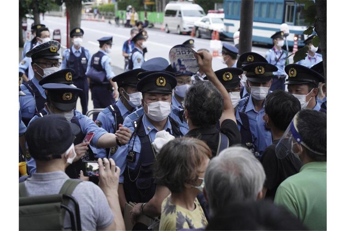 Demonstranten wurden vor Beginn der Olympia-Schlussfeier in Tokio von Polizisten aufgehalten. Foto: Kantaro Komiya/AP/dpa