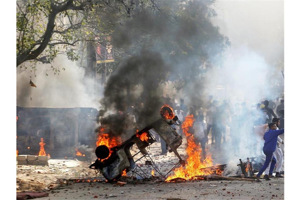 Demonstranten zünden ein Fahrzeug in Neu Delhi an. Foto: Str/Xinhua/dpa