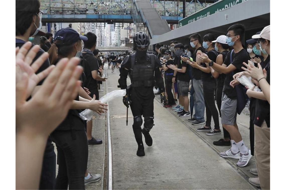 Peking verurteilt „schreckliche Vorfälle“ in Hongkong Demonstrationsteilnehmer jubeln bei einem Protest einem mit Protektoren und Schutzweste gekleideten Demonstranten zu. Foto: Vincent Yu/AP