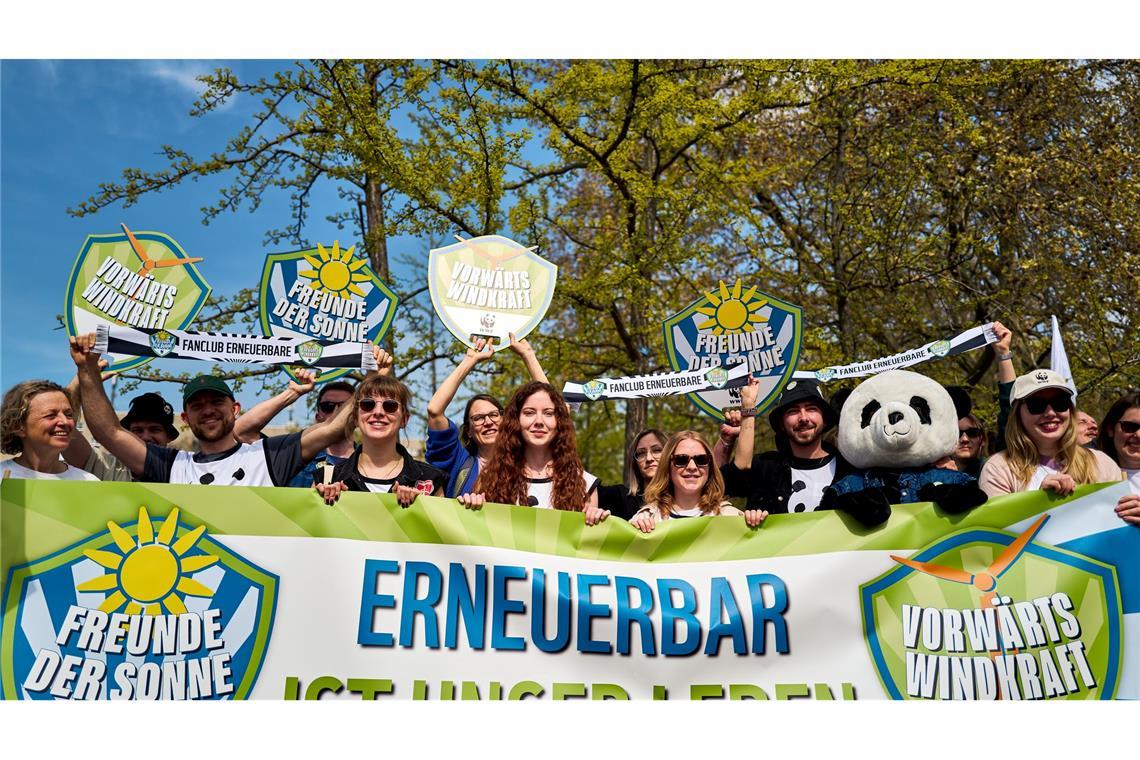 Demonstrierende halten ein Banner und Schilder in die Höhe, darunter eine Person im Pandakostüm.