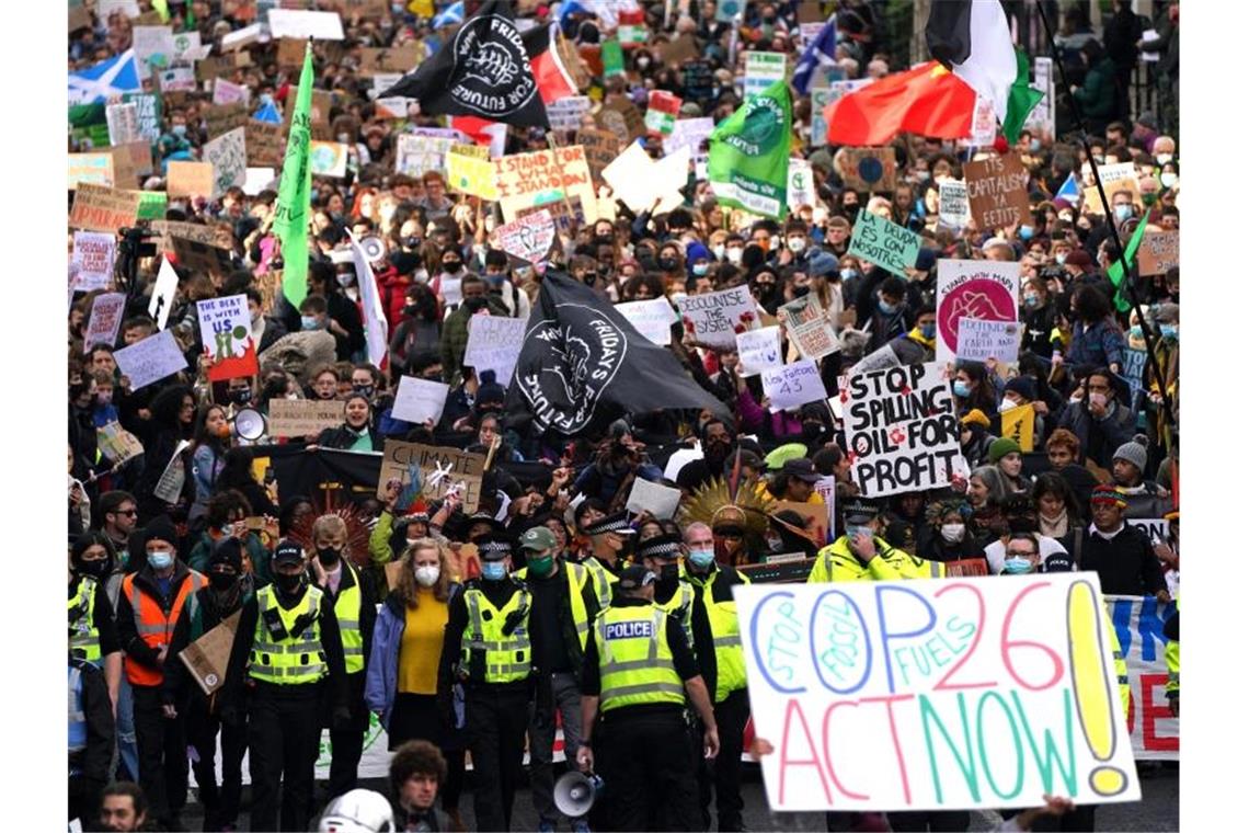 „Klimagerechtigkeit jetzt“ - Globale Proteste zur COP26 Demonstrierende ziehen mit Flaggen und Schildern durch die Straßen von Glasgow. Foto: Andrew Milligan/PA/dpa
