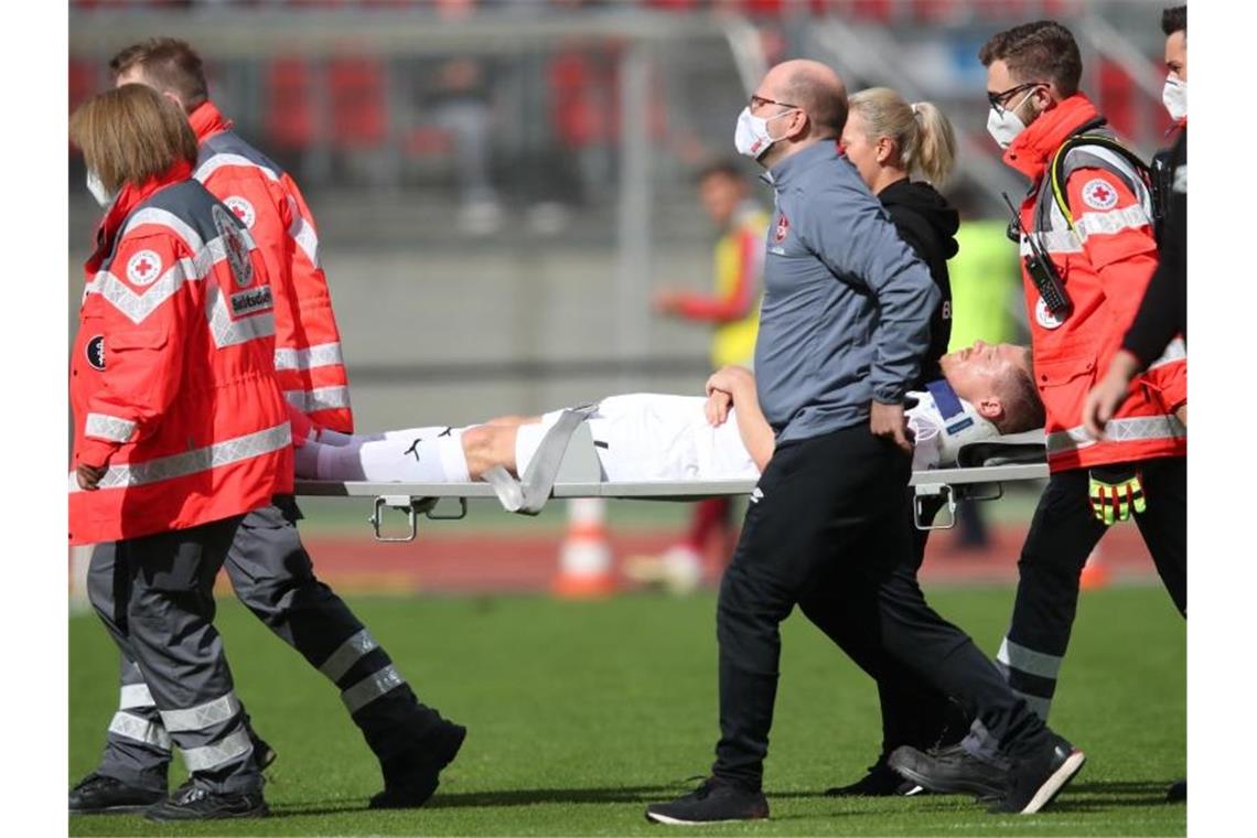 Denis Linsmayer (M) wird verletzt vom Platz getragen. Foto: Daniel Karmann/dpa/Archivbild