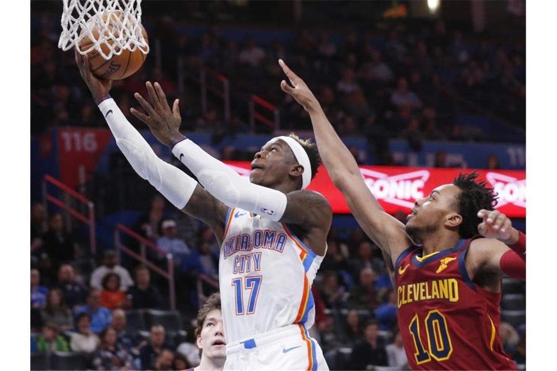 Dennis Schröder (l) von Oklahoma City Thunder setzt sich am Korb gegen Darius Garland von den Cleveland Cavaliers durch. Foto: Sue Ogrocki/AP/dpa