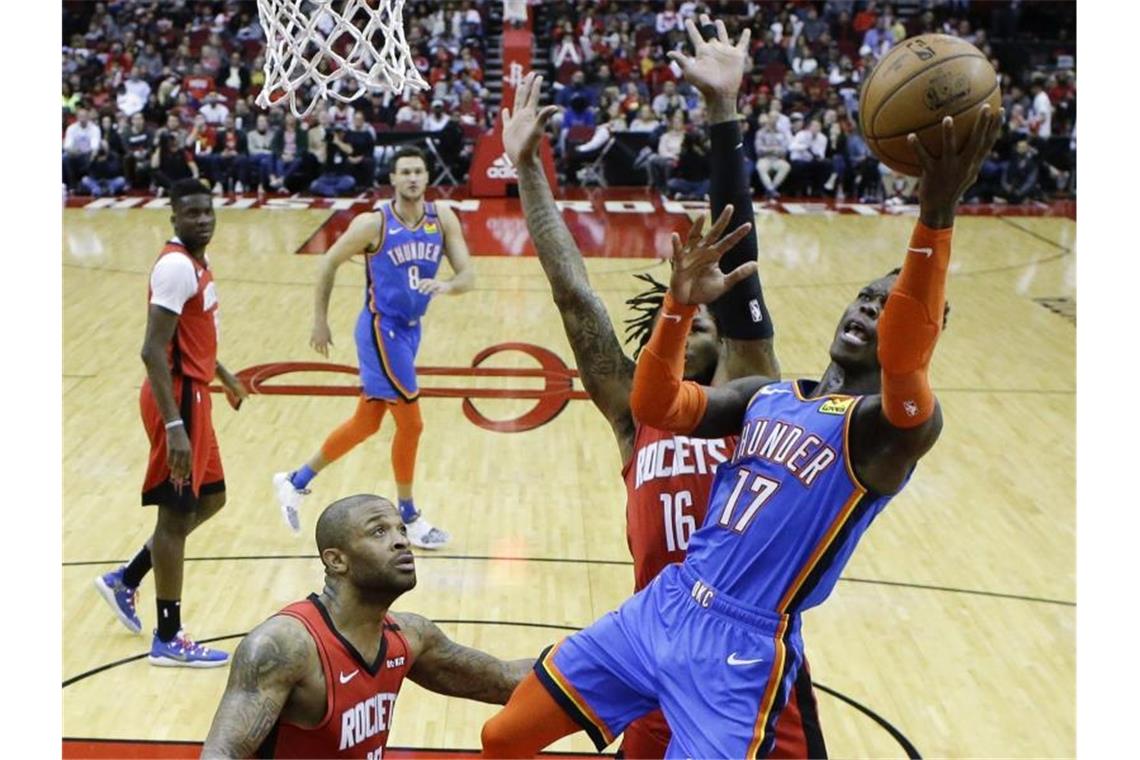 Dennis Schröder (r/17) von den Oklahoma City Thunder setzt sich am Korb gegen Ben McLemore (M) von den Houston Rockets durch. Foto: Eric Christian Smith/AP/dpa