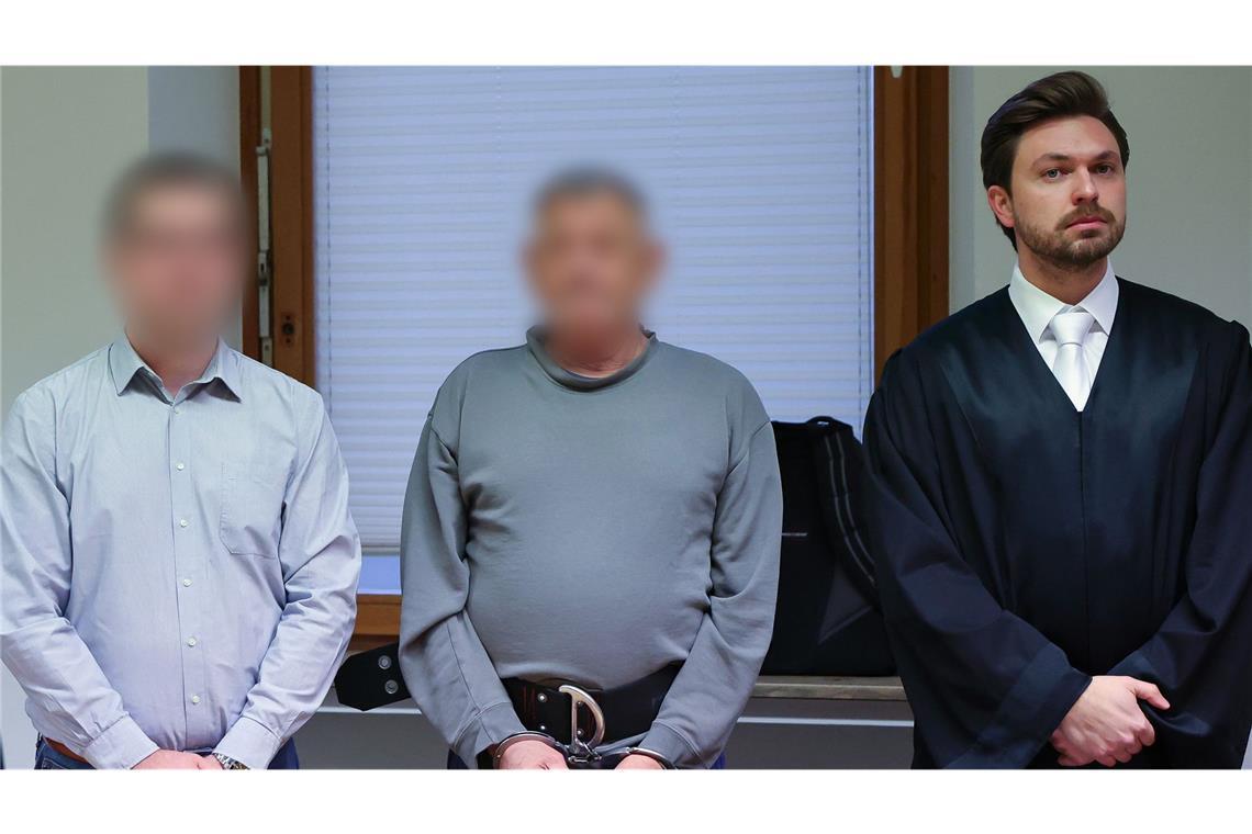 Der 71 Jahre alte Angeklagte aus den USA (M) steht zu Prozessbeginn zwischen dem Übersetzer (l) und seinem Strafverteidiger Johannes Makepeace (r) im Sitzungssaal am Landgericht Schweinfurt.
