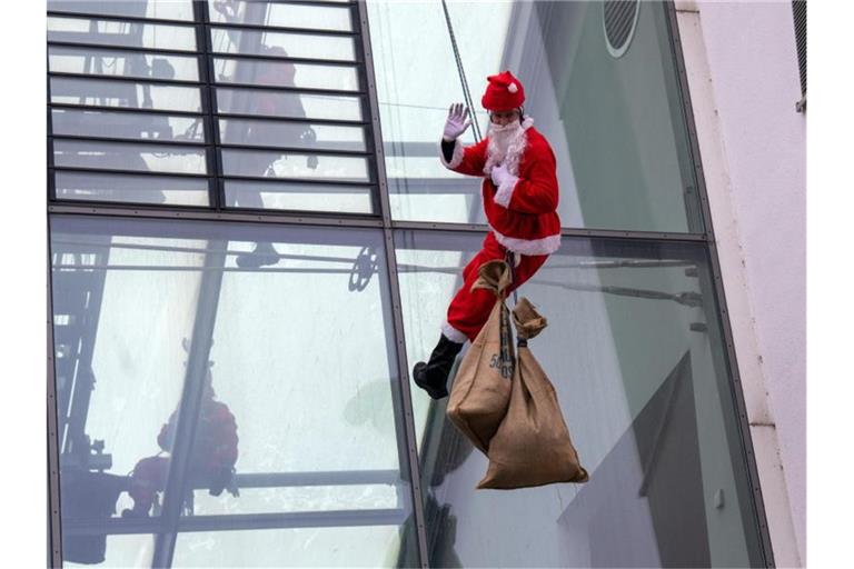 Der als Nikolaus verkleideter Feuerwehrmann seilt sich an der Uni-Kinderklinik ab. Foto: Stefan Puchner/dpa