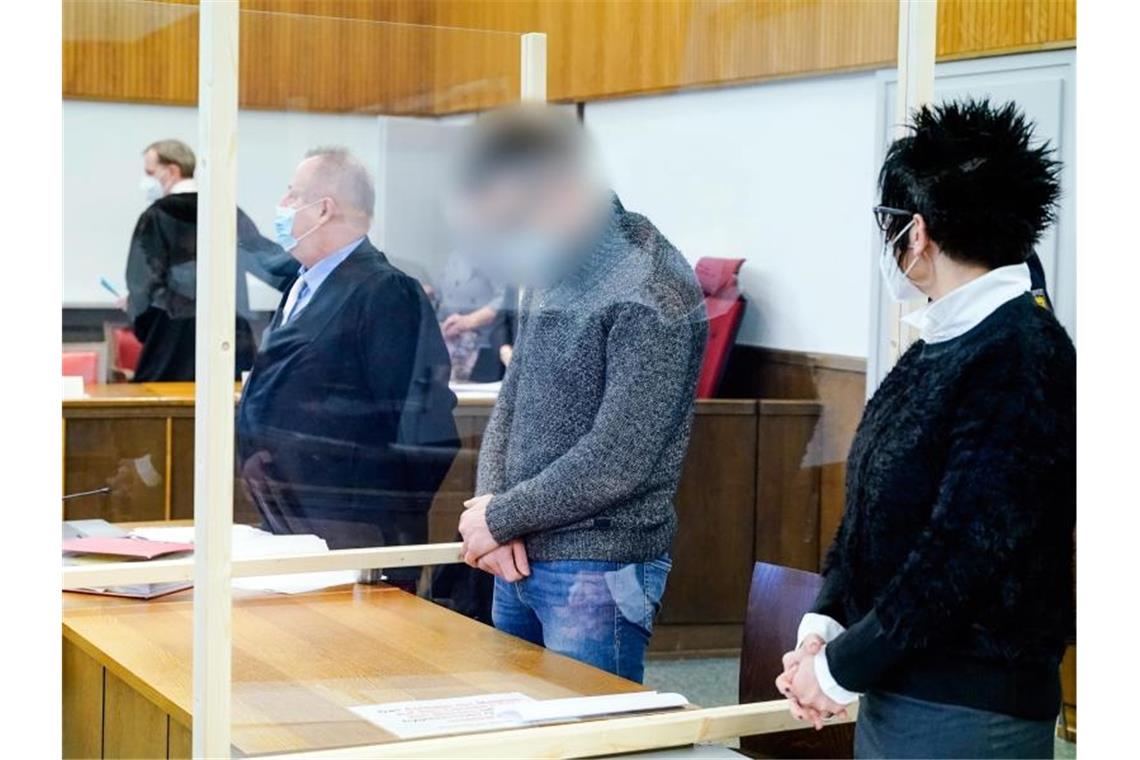Prozess nach Supermarkt-Überfall mit Staubsauger begonnen Der Angeklagte Constantin B. (2.v.r.) steht im Verhandlungssaal des Landgerichts. Er soll mit drei weiteren Komplizen im Dezember 2019 einen Supermarkt in Tauberbischofsheim überfallen haben. Das Kuriose an der Straftat war den Behörden zufolge, dass die Täter einen Staubsauger dabei hatten, mit dem das Geld - etwa 57 000 Euro - aus dem Tresor gesaugt worden sei. Foto: Uwe Anspach/dpa
