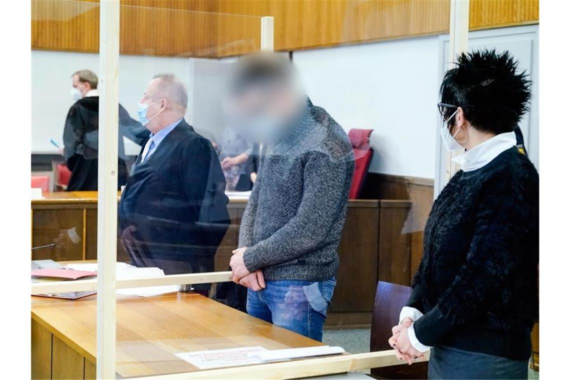 Der Angeklagte Constantin B. (2.v.r.) steht im Verhandlungssaal des Landgerichts. Er soll mit drei weiteren Komplizen im Dezember 2019 einen Supermarkt in Tauberbischofsheim überfallen haben. Das Kuriose an der Straftat war den Behörden zufolge, dass die Täter einen Staubsauger dabei hatten, mit dem das Geld - etwa 57 000 Euro - aus dem Tresor gesaugt worden sei. Foto: Uwe Anspach/dpa