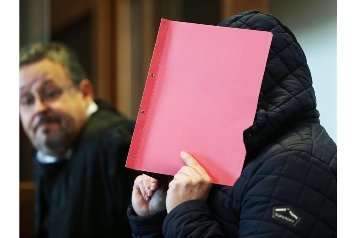 Der Angeklagte im Prozess wegen schweren sexuellen Missbrauchs hält sich im Gerichtssaal eine Mappe vor das Gesicht. Foto: Oliver Berg/dpa