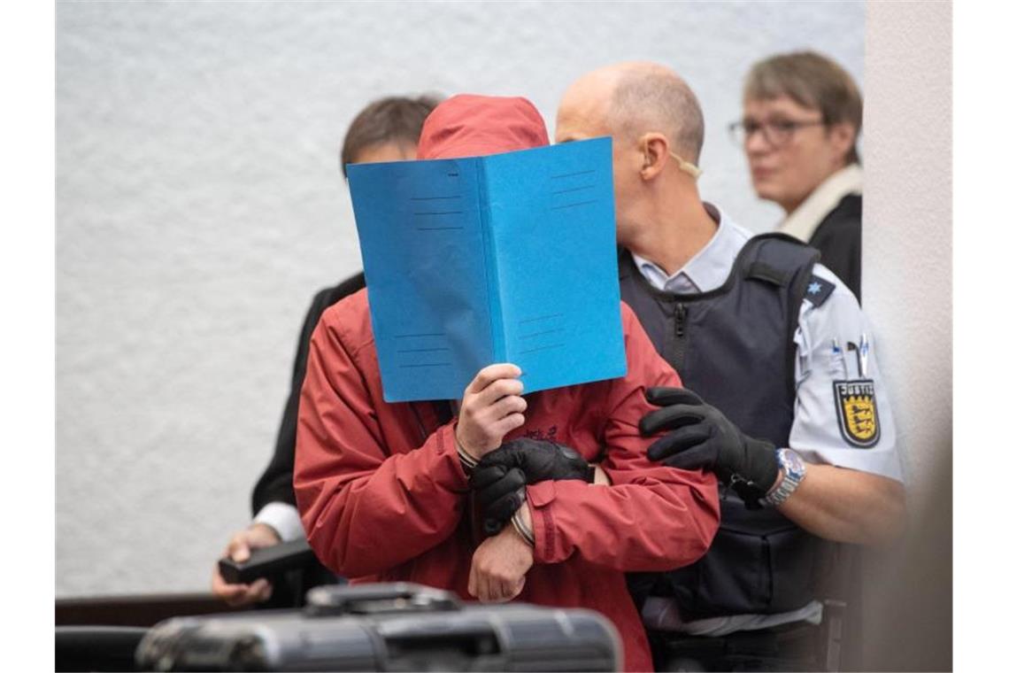 Der Angeklagte in einem Mordprozess nach einem tödlichem Unfall wird von einem Justizbeamten in einen Gerichtssaal des Landgerichts Stuttgart geführt. Foto: Marijan Murat/dpa