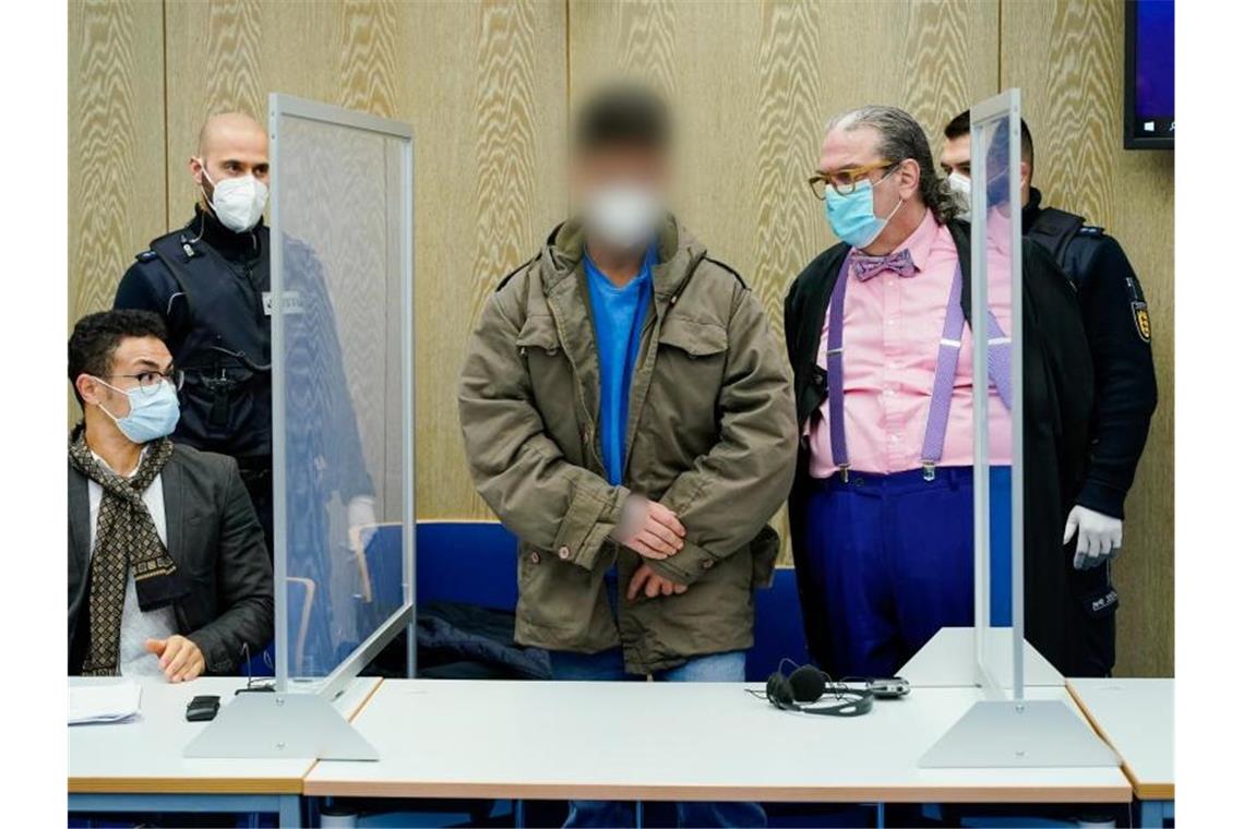 „Grausam und gefühllos“: Prozess um Mord mit Sektflasche Der Angeklagte (M) steht im Verhandlungssaal des Landgerichts neben seinem Anwalt Steffen Kling (r) und dem am Tisch sitzenden Übersetzer. Foto: Uwe Anspach/dpa/Aktuell