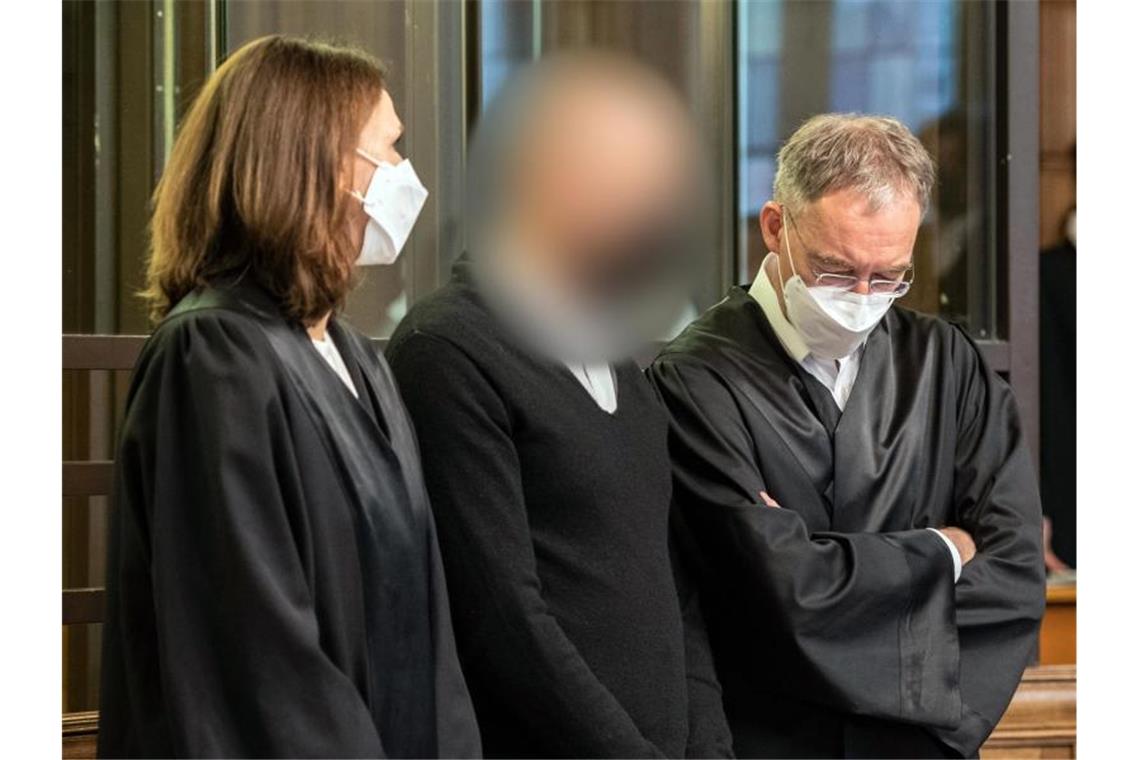Der Angeklagte (M) zwischen seinen Anwälten in Berlin. Foto: Paul Zinken/dpa