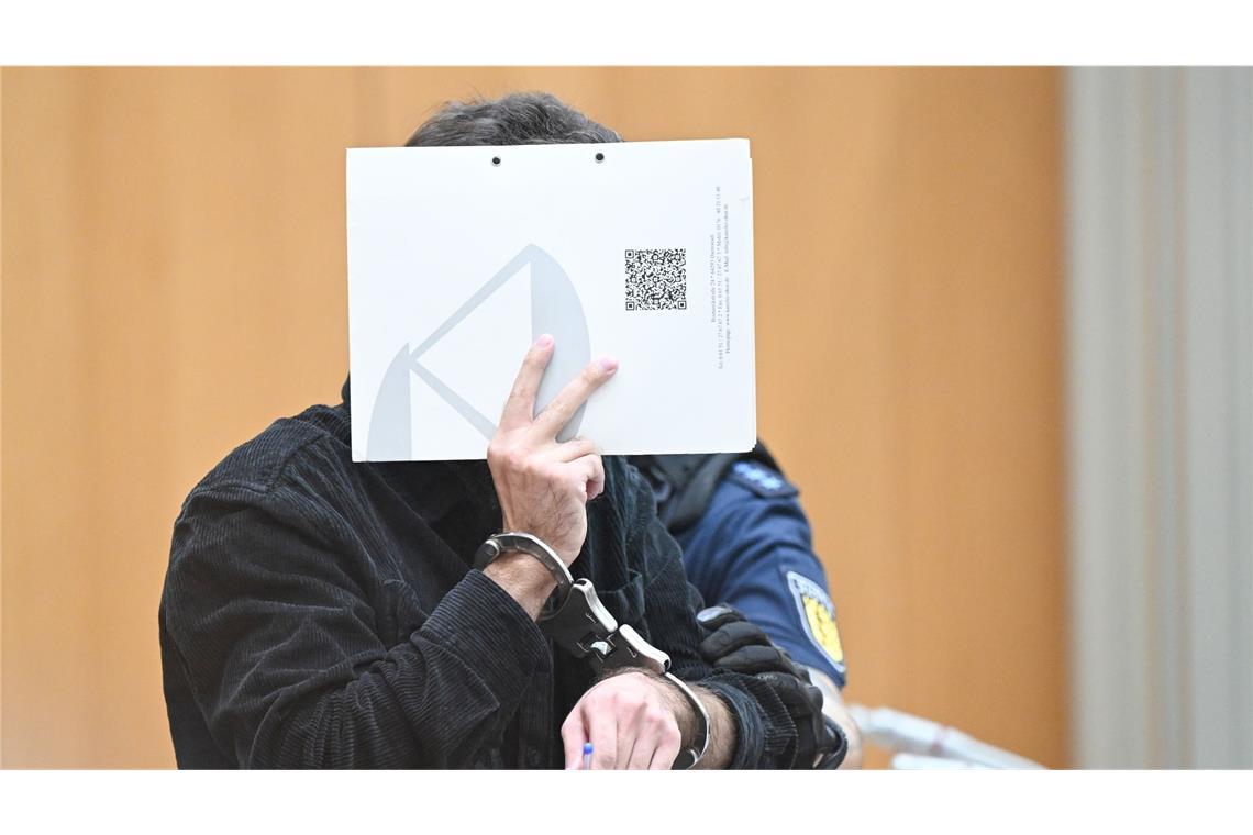 Urteil im Prozess um Messerangriff in Mannheim erwartet Der Angeklagte steht zu Beginn eines Verhandlungstages mit einem Aktenordner vor dem Gesicht im Gerichtssaal (Archivbild).