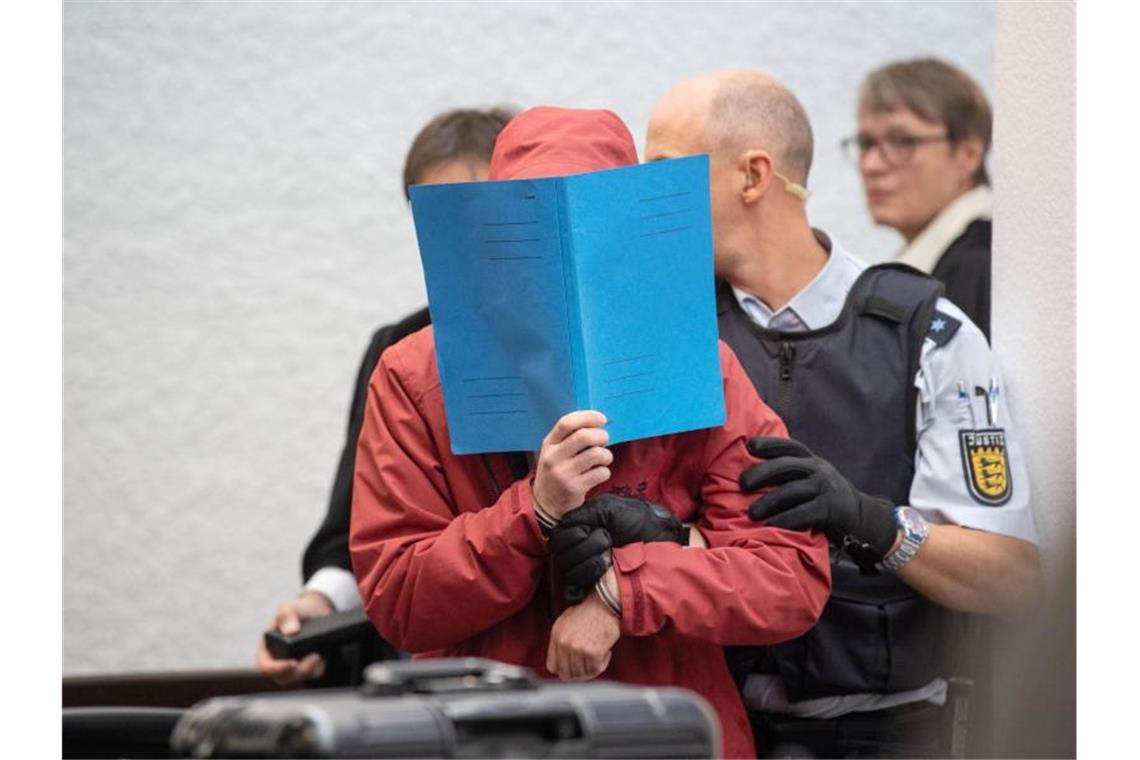Der Angeklagte wird von einem Justizbeamten in einen Gerichtssaal des Landgerichts Stuttgart geführt. Foto: Marijan Murat