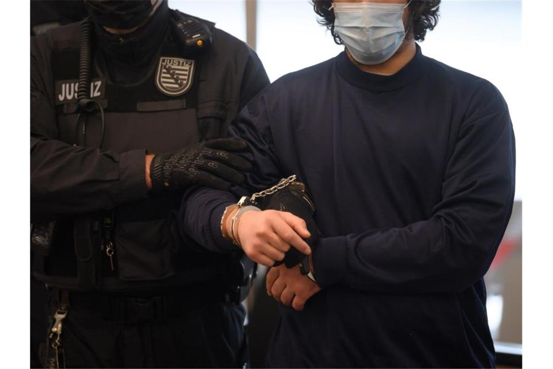 Lebenslang für tödliche Messerattacke auf schwules Paar Der Angeklagte wird vor der Urteilsverkündung von Justizbeamten in den Verhandlungssaal des OLG Dresden geführt. Foto: Robert Michael/dpa-Zentralbild Pool/dpa