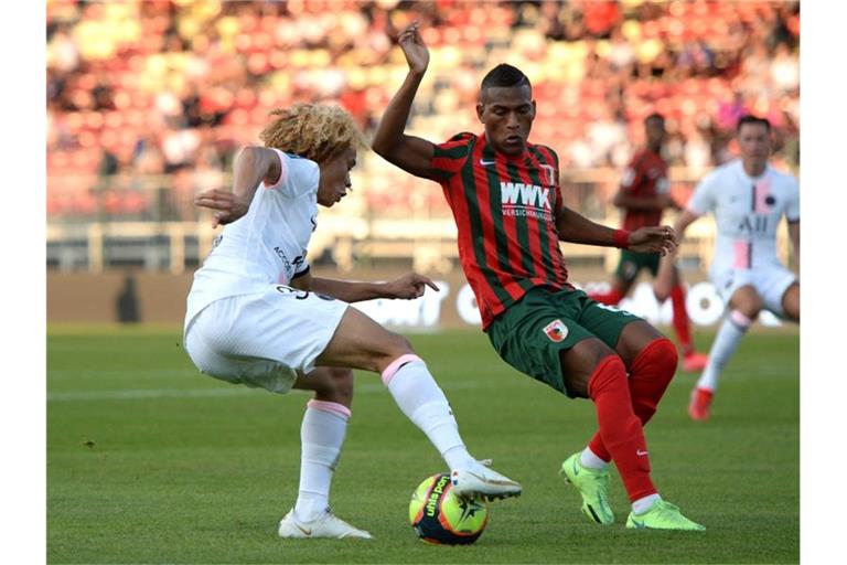 Der Augsburger Carlos Gruezo (r) im Zweikampf mit PSG-Talent Xavi Simons. Foto: Guillaume Souvant/AFP/dpa