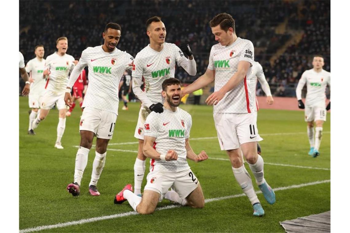 Matchwinner nach schwerer Zeit: Augsburgs Caligiuri Der Augsburger Daniel Caligiuri (M. unten) lässt sich feiern. Foto: Friso Gentsch/dpa