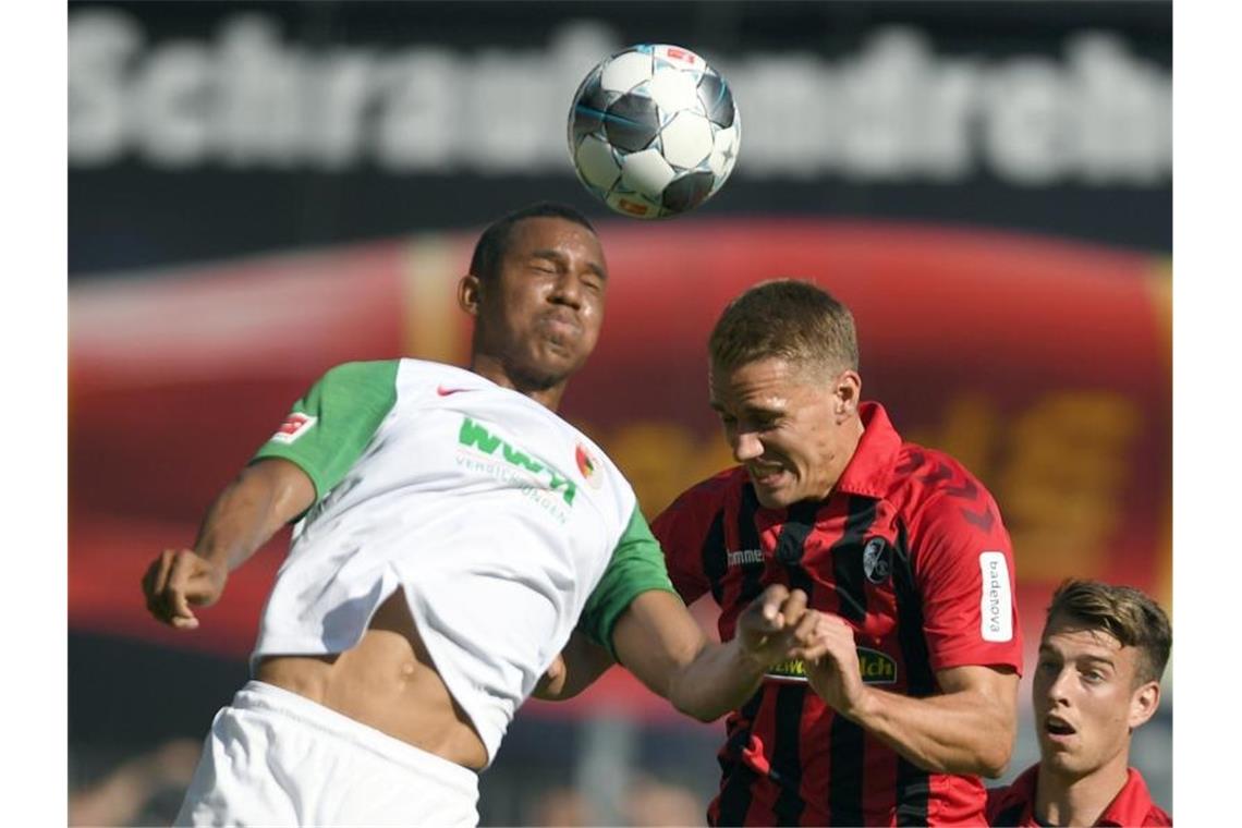 Der Augsburger Ohis Felix Uduokhai (l) und Nils Petersen vom SC Freiburg gegen zum Ball. Foto: Patrick Seeger