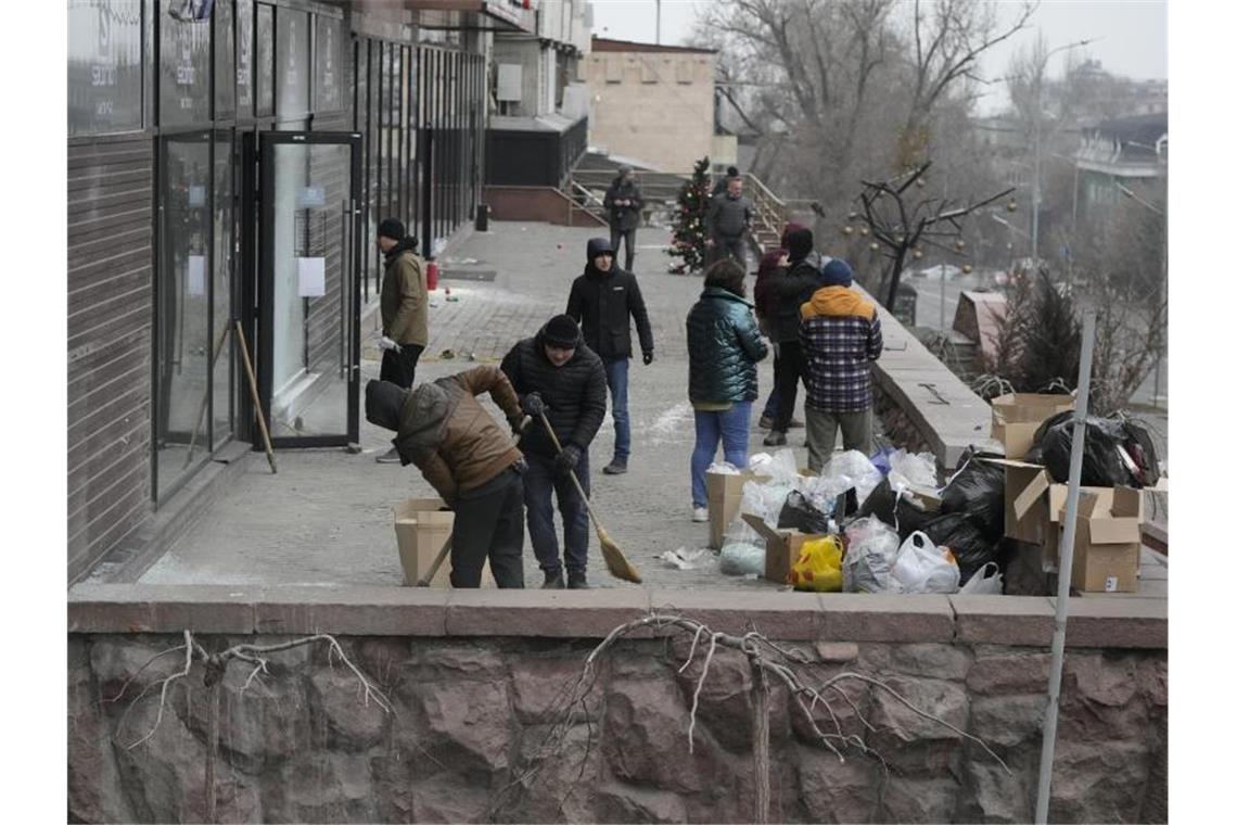 Unruhen in Kasachstan: Präsident spricht von „Staatsstreich“ Der Bereich vor einem Laden, der bei Zusammenstößen beschädigt wurde, wird gesäubert. Foto: Sergei Grits/AP/dpa