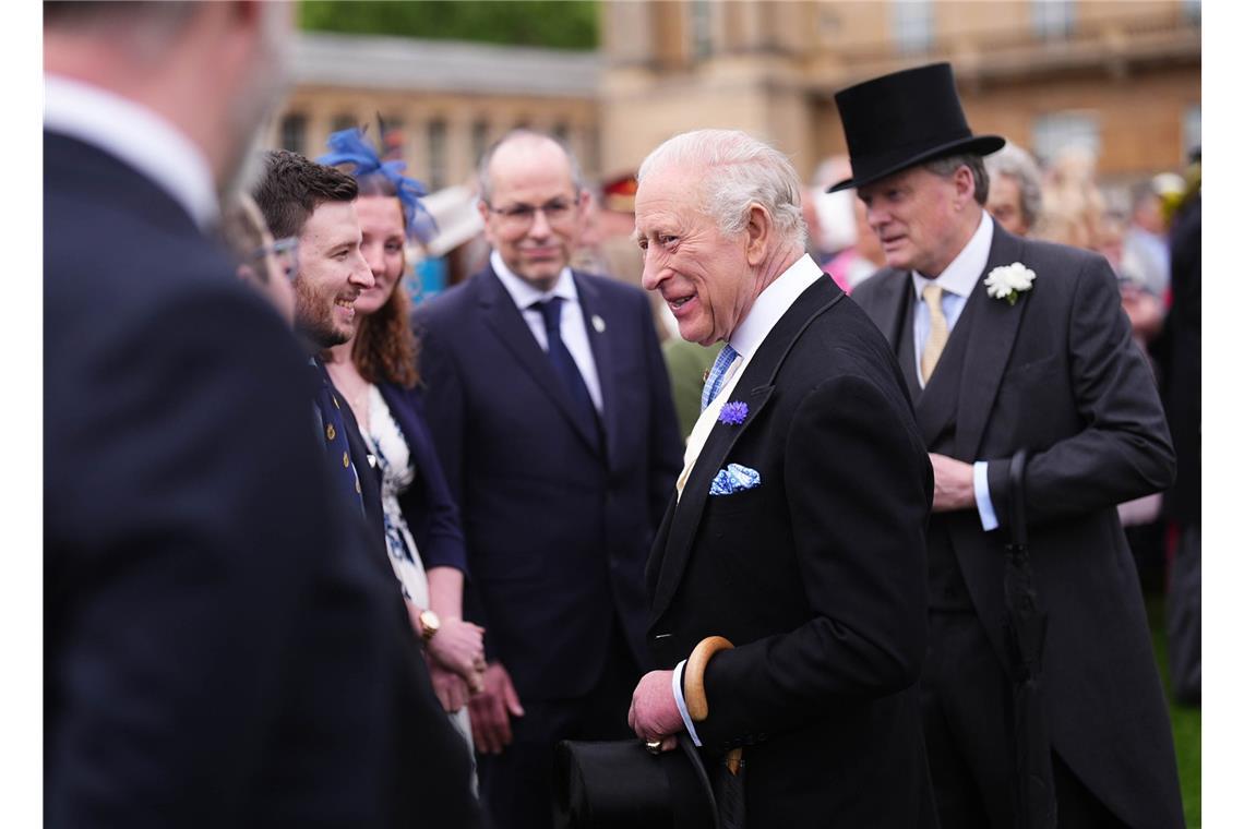 Der britische König Charles III. (M.) unterhält sich mit Gästen während der jährlichen Gartenparty im Buckingham Palace.