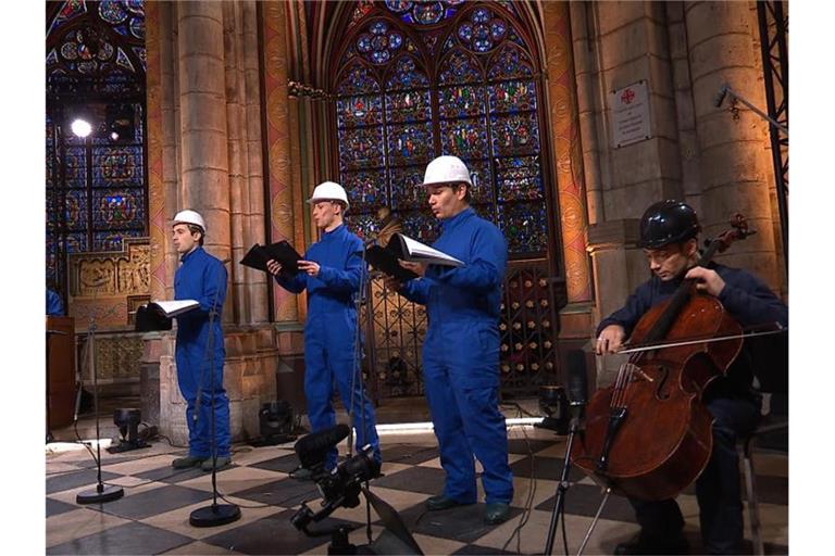 Der Cellist Gautier Capucon (r) und der Chor der Kathedrale Notre Dame zeichnen ein Weihnachtskonzert auf. Foto: Musique Sacree à Notre-Dame de Paris/MSNDP/AP/dpa