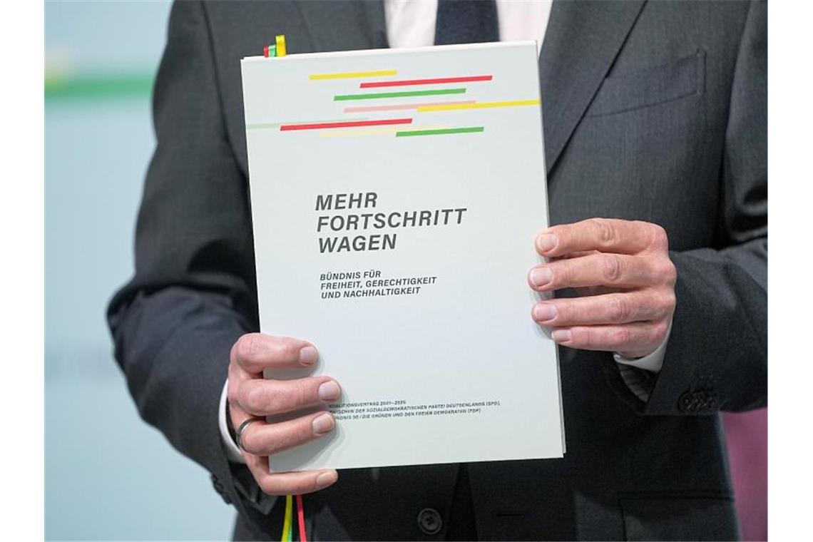 Der designierte Bundeskanzler Olaf Scholz mit dem Vertrag seiner Regierungskoalition. Foto: Michael Kappeler/dpa