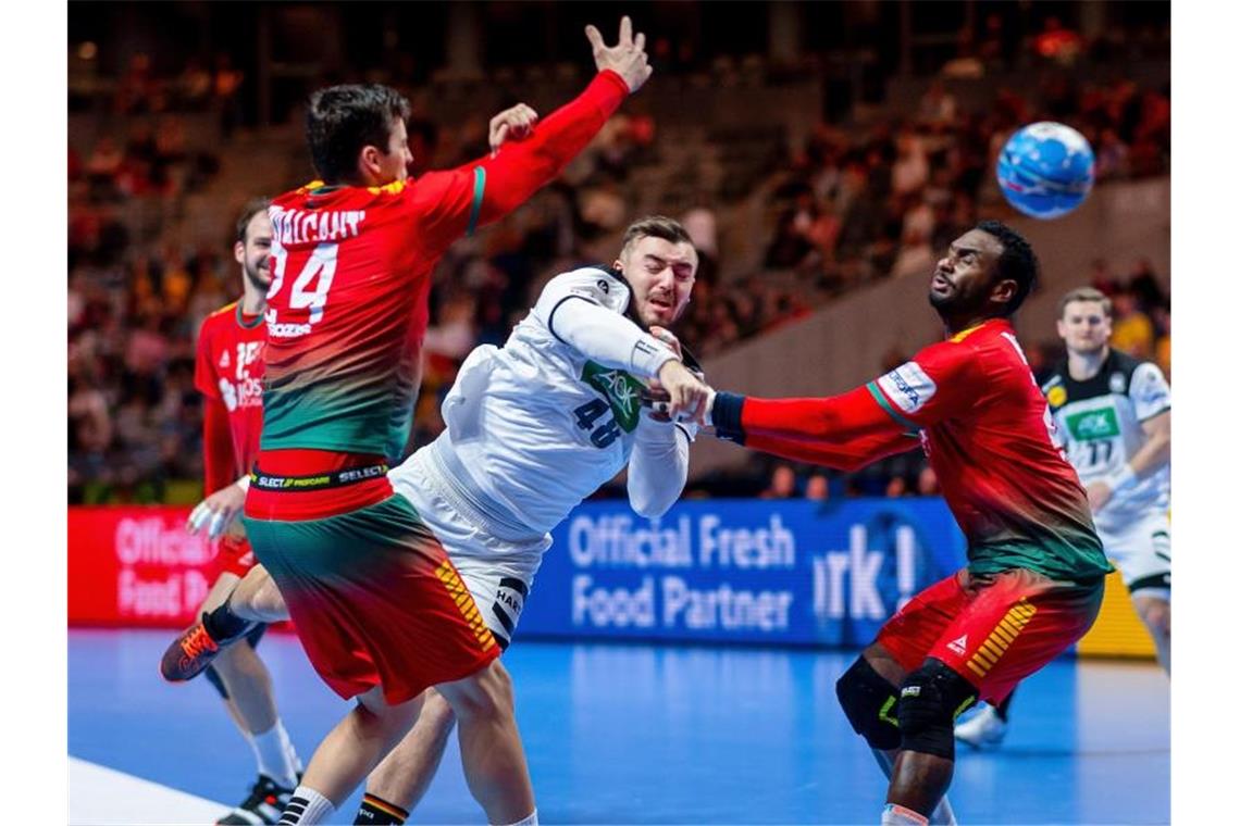 Deutsche Handballer nach Sieg gegen Portugal Fünfter Der deutsche Spieler Jannik Kohlbacher (M) setzt sich gegen Alexandre Cavalcanti (l) und Alexis Borges (r) durch. Foto: Sascha Klahn/dpa