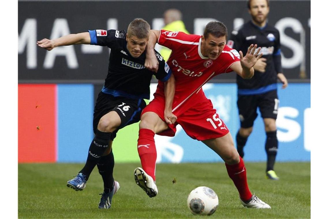 Der Düsseldorfer Ivan Paurevic (r) und der Paderborner Johannes Wurtz kämpfen um den Ball. Foto: Roland Weihrauch/Archiv