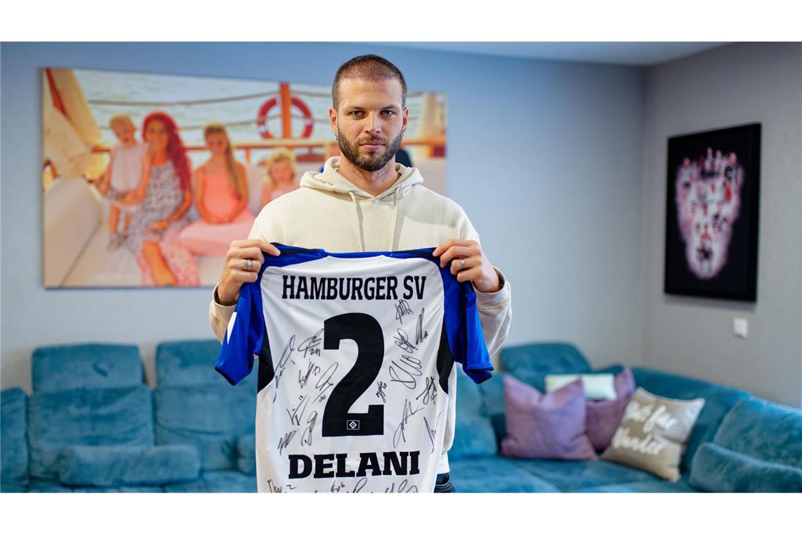 Der ehemalige Fußballspieler Dennis Diekmeier hält in seiner Wohnung ein Trikot des Hamburger SV mit dem Namen seiner ältesten Tochter in den Händen.