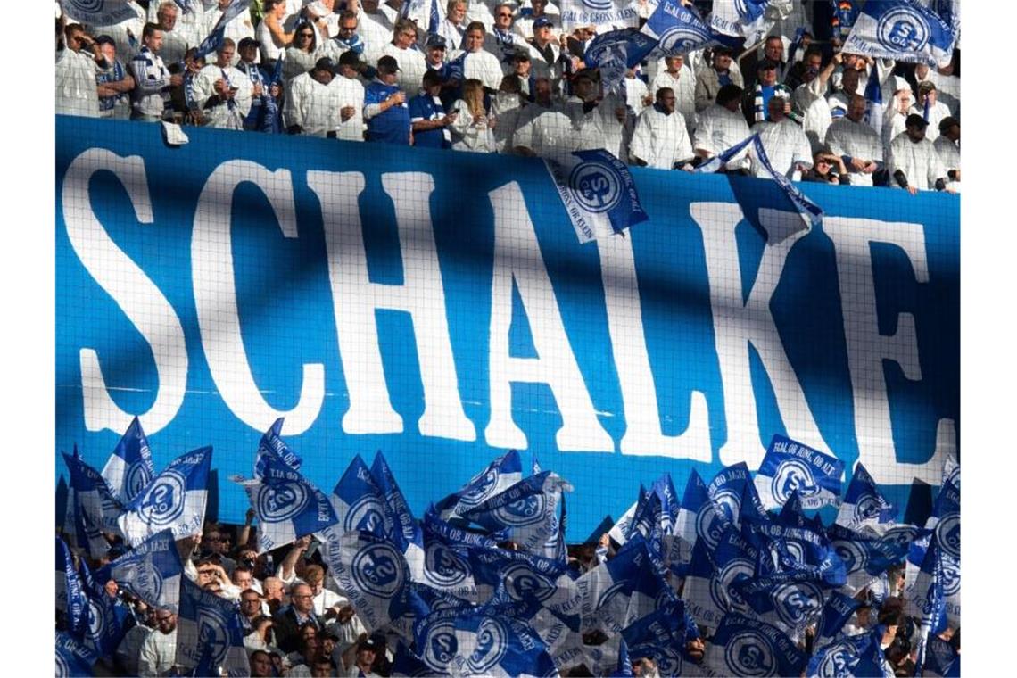 Der finanziell angeschlagene Bundesligaverein soll eine Bürgschaft erhalten - Schalke-Fans schwenken Fahnen. Foto: Bernd Thissen/dpa