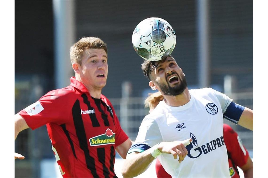 Der Freiburger Dominique Heintz und der Schalker Daniel Caligiuri (l-r.) am Werk. Foto: Uli Deck/dpa