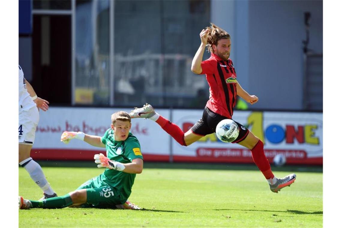 Der Freiburger Lucas Höler (r) erzielt das 3:0 gegen Schalke-Torwart Alexander Nübel (M), der das Nachsehen hat. Foto: Uli Deck/dpa